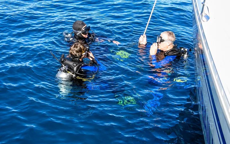 Dive boat with crew, turquoise water, Cabo cliffs