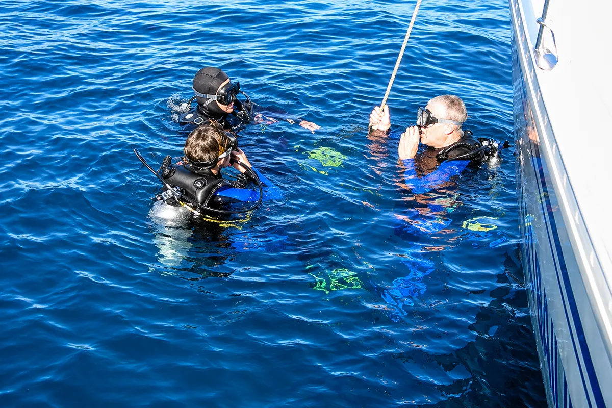 Dive boat with crew, turquoise water, Cabo cliffs